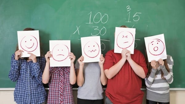 Students holding pictures of happy and sad faces