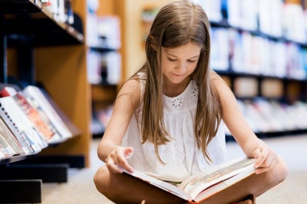 Focused girl with an open book, lost in the world of words.