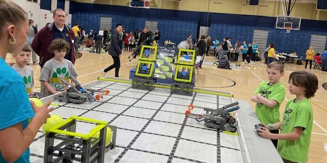 A group of elementary students using remotes to control robots